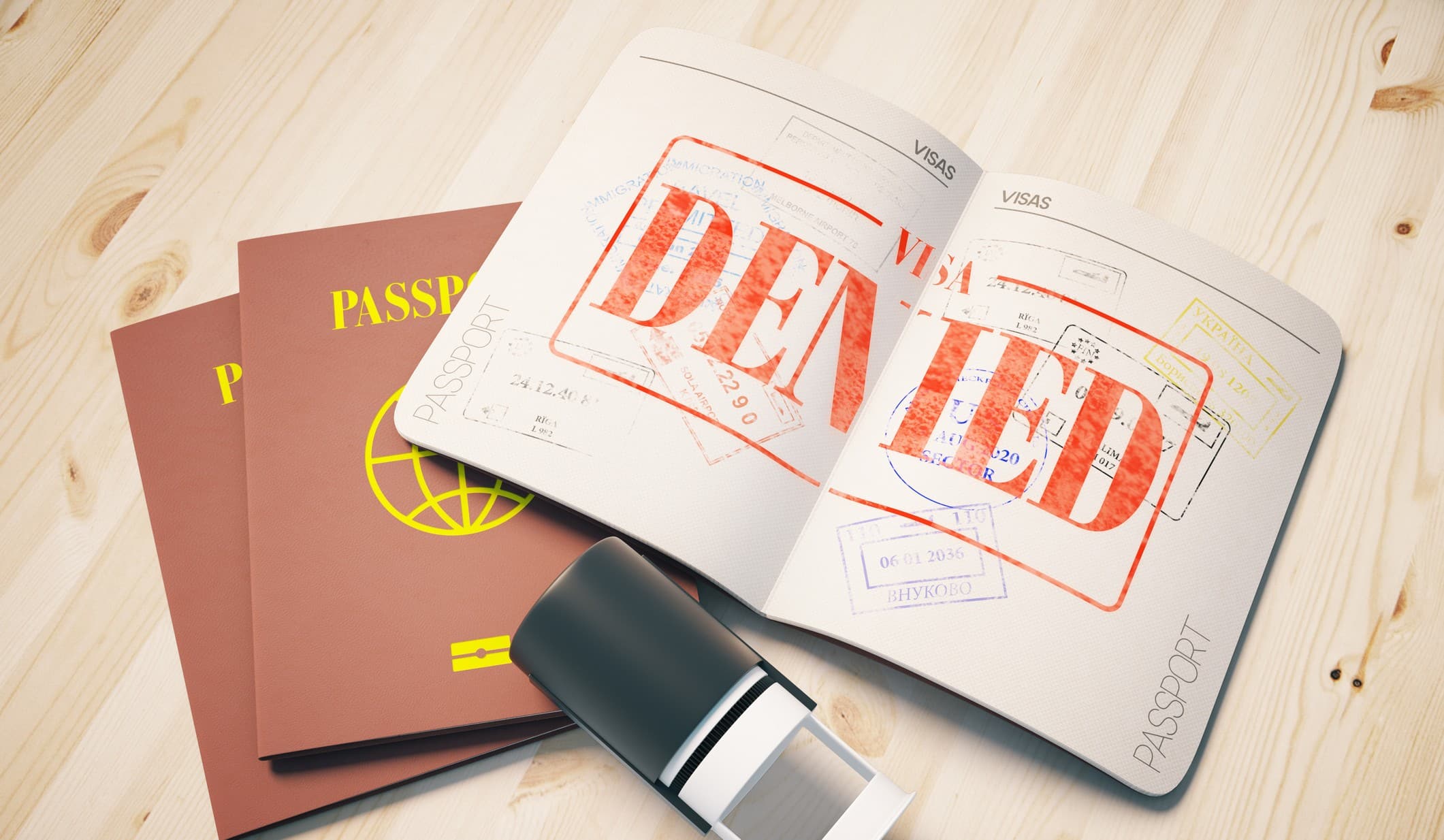 Passport with red denied visa stamp on wooden background